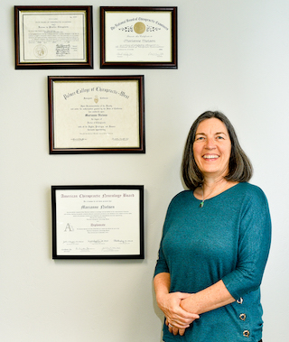 Los Gatos chiropractic neurologist Dr Marianne Nielsen stands next to her diplomas and certifications.